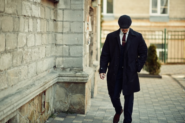 Retrato de hombre de negocios árabe inglés retro de los años 20 con traje oscuro, corbata y gorra plana.