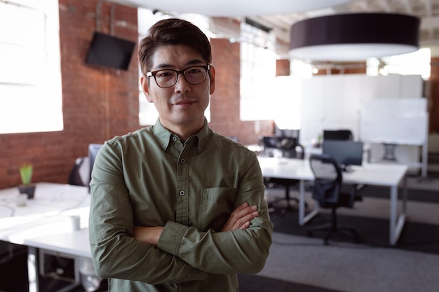 Foto retrato de un hombre de negocios asiático serio parado en el cargo con los brazos cruzados mirando a la cámara. trabajar en negocios en una oficina moderna.