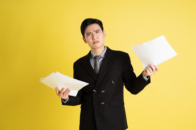 Foto retrato de un hombre de negocios asiático con traje y posando sobre un fondo amarillo