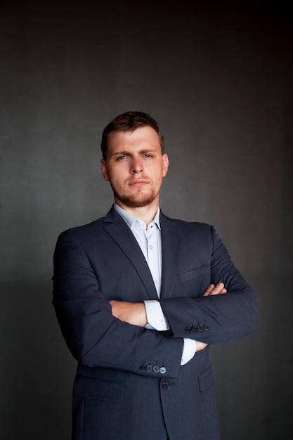 Retrato de un hombre de negocios bien vestido y confiado con los brazos cruzados de pie contra la pared