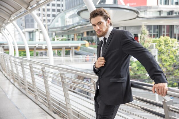 Foto retrato de un hombre de negocios confiado de pie en una pasarela elevada en la ciudad