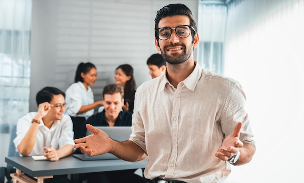 Retrato de un hombre de negocios con confianza y sonrisa feliz con el fondo de su colega y el equipo de negocios que trabajan en la oficina Trabajo en equipo del trabajador de la oficina y concepto positivo del lugar de trabajo Prudente