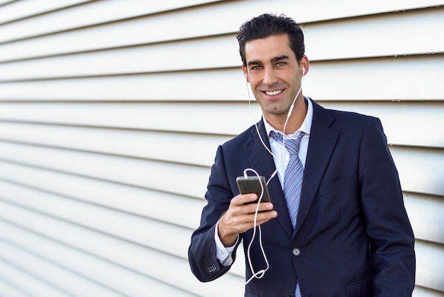 Foto retrato de un hombre de negocios escuchando música en auriculares con persianas