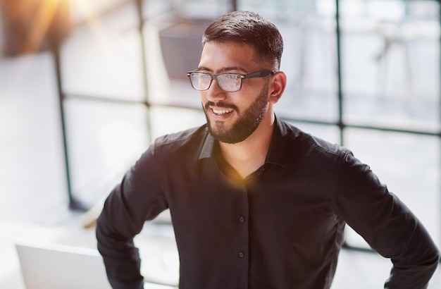 Retrato de hombre de negocios feliz confiado joven empresario de pie sonriendo mirando a la cámara