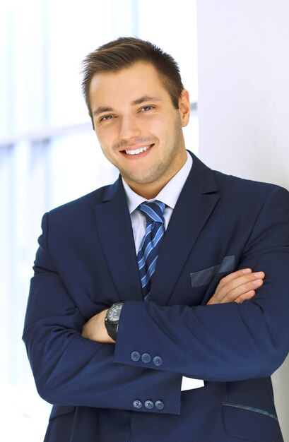 Retrato de un hombre de negocios feliz y sonriente en la oficina Trajes de chaqueta azul a sus brazos cruzados