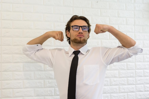 Foto retrato de un hombre de negocios flexionando los músculos mientras está de pie en la oficina