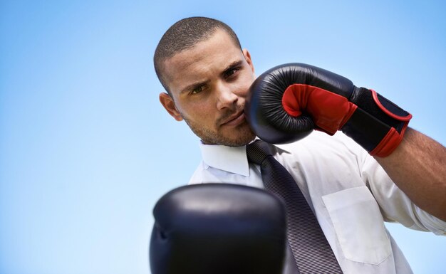 Foto retrato de hombre de negocios y guantes de boxeo para desafío o guerrero autodefensa y acondicionamiento físico en el estudio persona masculina fuerte y equipo para lucha o ejercicio espacial de maqueta y fondo azul