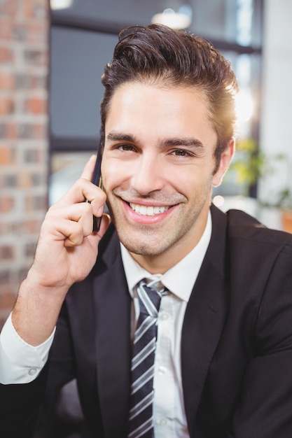 Retrato de hombre de negocios guapo hablando por teléfono móvil