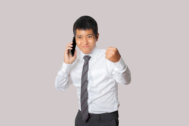 Retrato de hombre de negocios hablando de teléfono inteligente con gesto de ganador y celebrando la victoria feliz Concepto de expresión de cara de emoción humana Disparo de estudio aislado en espacio de copia de fondo gris