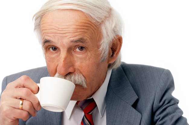 Retrato de un hombre de negocios mayor tomando café sobre blanco.