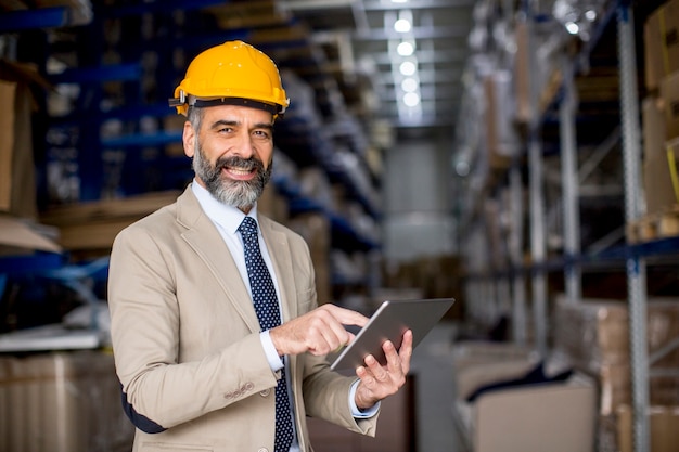 Retrato de hombre de negocios de mediana edad con tableta digital en fábrica