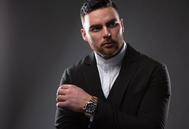 Retrato de un hombre de negocios de moda serio con barba vestido con un traje negro y camisa blanca