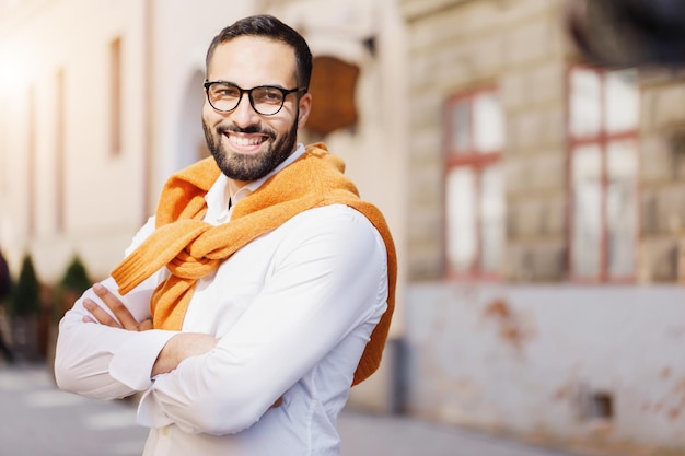 Retrato de un hombre de negocios multicultural barbudo parado en la calle y sonriendo