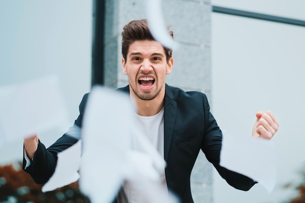 Foto retrato de un hombre de negocios de pie junto a los papeles en el aire