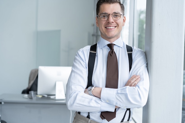 Foto retrato de hombre de negocios de pie junto a la ventana en la oficina.