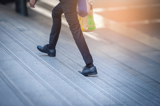 El retrato del hombre de negocios que camina en las escaleras va a una ciudad.