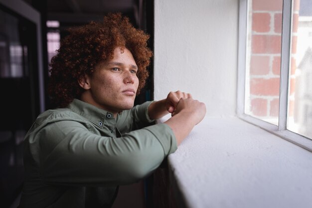 Foto retrato de un hombre de negocios de raza mixta parado en la oficina y mirando la ventana