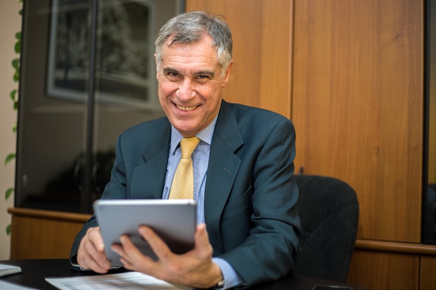 Retrato de hombre de negocios senior en la oficina usando tableta