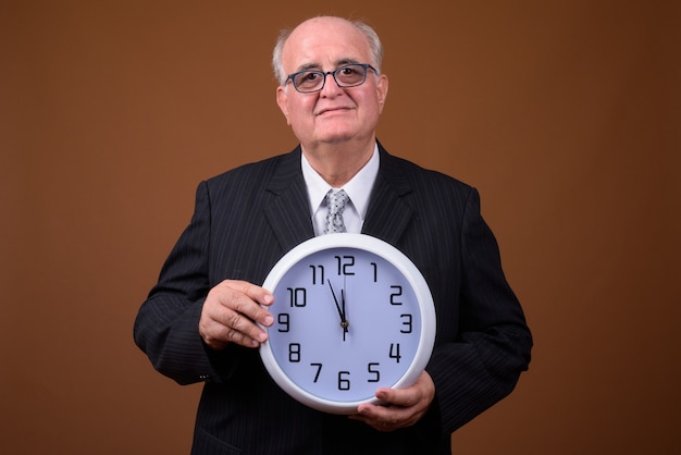 Retrato de hombre de negocios senior con sobrepeso sosteniendo el reloj