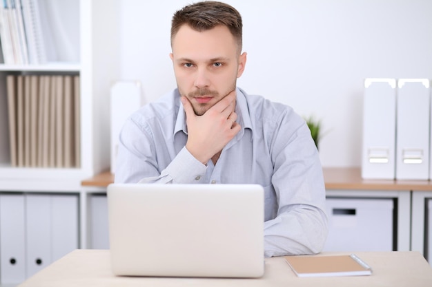 Retrato de hombre de negocios sentado en el escritorio en el lugar de trabajo de la oficina.