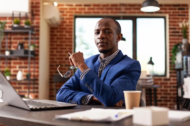 Retrato de un hombre de negocios sentado en el escritorio para trabajar en un proyecto y una estrategia con una laptop. Empleado de la empresa que trabaja en la computadora para planificar la estrategia de marketing y hacer el papeleo. persona con trabajo