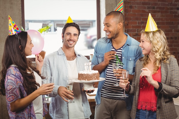 Retrato del hombre de negocios sonriente que sostiene la torta durante la celebración del cumpleaños