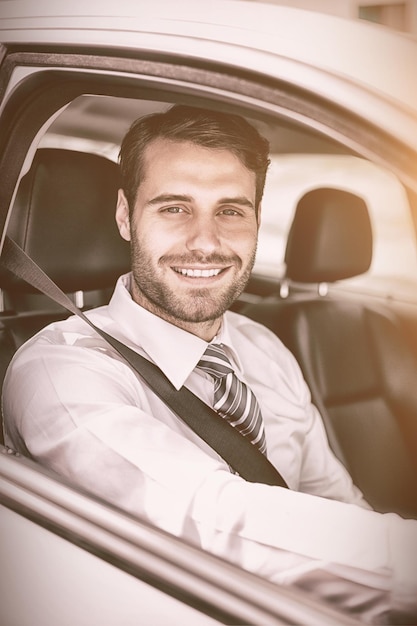 Retrato de un hombre de negocios sonriente sentado en el asiento del conductor en su auto