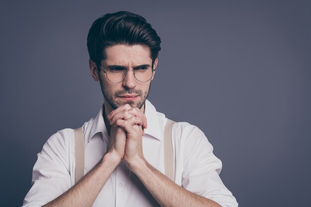 Retrato de hombre de negocios sosteniendo los brazos juntos con los dedos cruzados debajo de la barbilla.