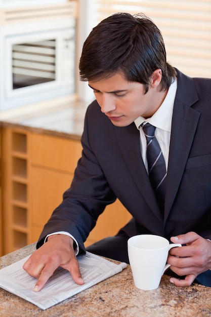 Retrato de un hombre de negocios tomando café mientras lee un newspa