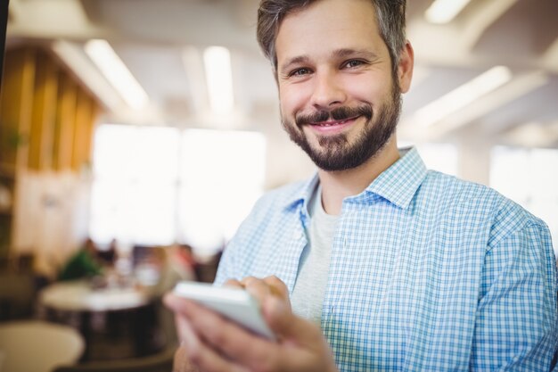 Retrato de hombre de negocios usando el teléfono en la cafetería de la oficina