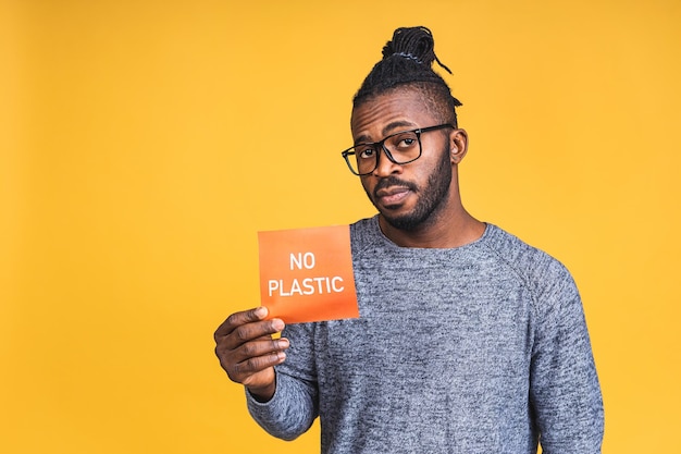 Retrato de un hombre negro afroamericano joven sonriente feliz alegre que se encuentran aisladas sobre fondo amarillo. Sin concepto de plástico cero residuos.