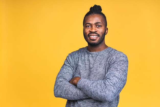 Retrato de un hombre negro afroamericano joven sonriente feliz alegre que se encuentran aisladas sobre fondo amarillo.