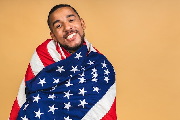 Retrato de un hombre negro afroamericano positivo que sostiene la bandera de EE. UU. Aislado sobre fondo beige