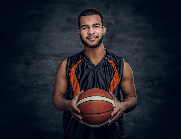 Foto retrato de un hombre negro barbudo sostiene una pelota de baloncesto.