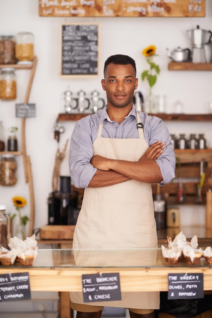 Foto retrato de hombre negro y camarero con los brazos cruzados en un café con orgullo por su carrera o trabajo barista serio y confianza de una persona africana de nigeria en un restaurante, una pequeña empresa y una cafetería