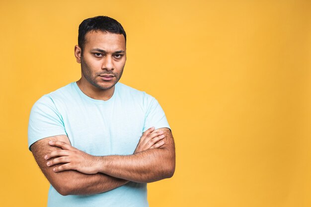 Retrato de un hombre negro indio afroamericano joven de pensamiento serio que se encuentran aisladas sobre fondo amarillo.