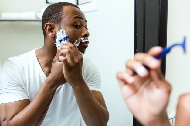 Retrato de hombre negro joven guapo afeitado en el baño de su casa.