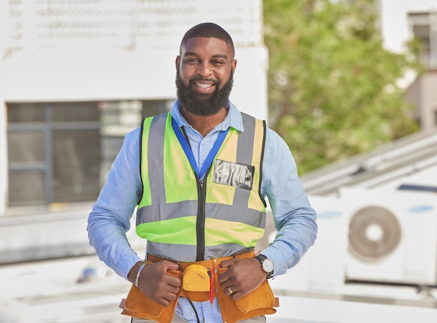 Retrato de hombre negro y mantenimiento de la construcción e ingeniero con sonrisa y arquitectura contratista masculino africano al aire libre renovación profesional e infraestructura urbana manitas con herramientas