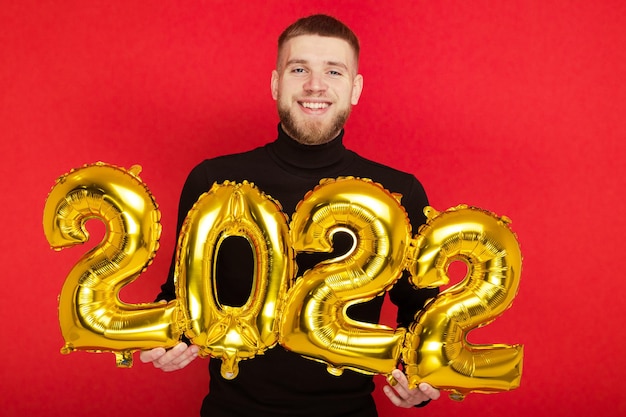 Retrato de un hombre con los números 2022 sobre un fondo rojo. El próximo año nuevo