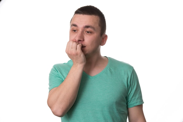 Retrato del hombre pensante con los dedos en la boca mordiendo la uña emoción negativa expresión facial aislado sobre fondo blanco.