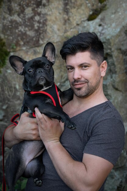 Retrato de un hombre con un perro de pie contra la pared