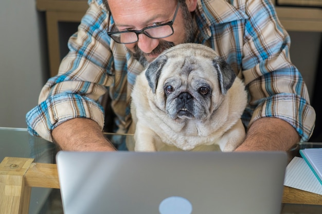 Retrato de hombre y perro trabajando juntos en casa con concepto de computadora portátil de estilo de vida de trabajo inteligente gratis personas caucásicas escribiendo en el teclado en la estación de trabajo trabajo en línea moderno negocio digital