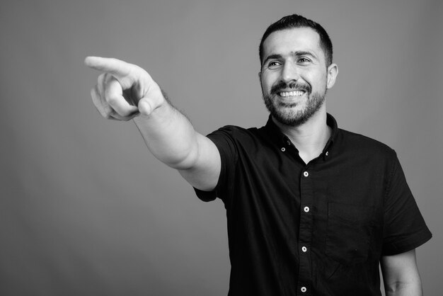 Retrato de hombre persa barbudo guapo con camisa negra sobre gris en blanco y negro