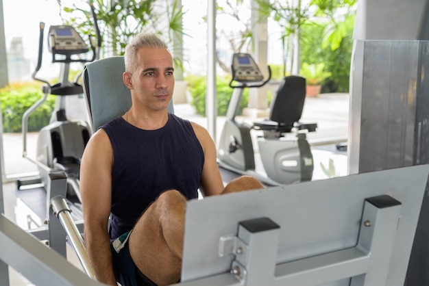 Retrato de hombre persa guapo maduro con cabello gris haciendo ejercicio en el gimnasio