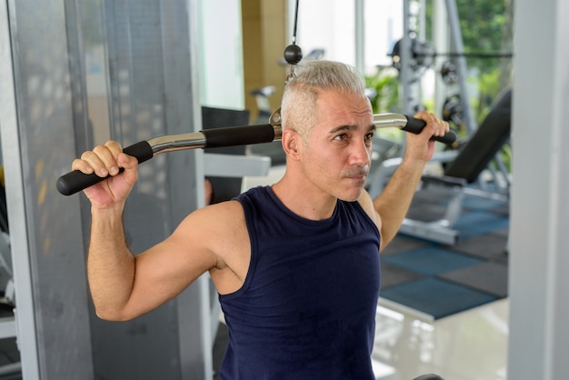 Retrato de hombre persa guapo maduro con cabello gris haciendo ejercicio en el gimnasio