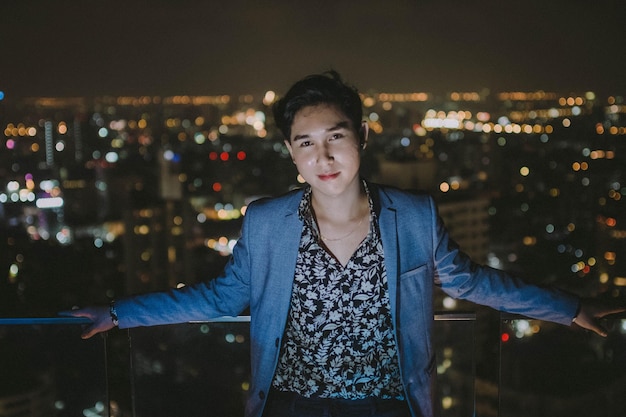 Foto retrato de un hombre de pie frente a una ciudad iluminada por la noche