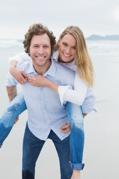 Retrato de un hombre piggybacking mujer en la playa