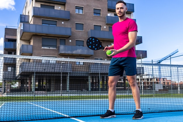 Foto retrato de un hombre posando mirando a la cámara preparado para jugar un juego de pickleball en una cancha callejera pickleball se está convirtiendo en un deporte muy popular en todo el mundo