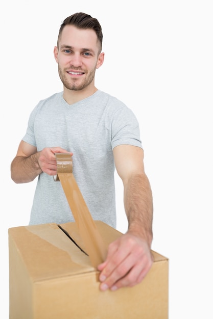 Foto retrato del hombre que sella la caja de cartón con la cinta de embalaje