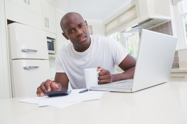 Retrato de un hombre que trabaja y que usa su computadora portátil y que mira la cámara